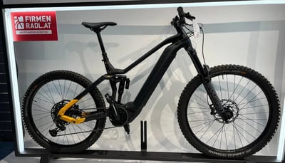 Schwarzes E-Mountainbike mit Federung und gelben Details im Ständer. Schwarzes E-Mountainbike mit Federung und gelben Details im Ständer.