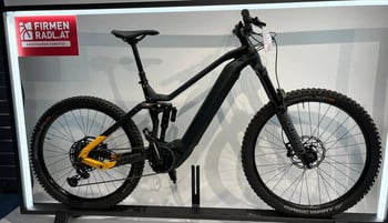 Schwarzes E-Mountainbike mit Federung und gelben Details im Ständer.