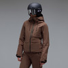 Eine Frau in einer braunen Skijacke und Hose mit Helm und Brille.