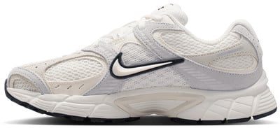 Fehér Nike cipő szürke és bézs részletekkel és fekete logóval. Fehér Nike cipő szürke és bézs részletekkel és fekete logóval.