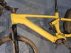 Ein gelbes E-Bike mit Federung und schwarzen Details auf blauem Hintergrund.
