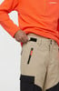 Ein Mann trägt ein orangefarbenes Sweatshirt und eine beige Hose mit schwarzen Details.