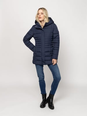 Egy nő sötétkék puffer dzsekiben és farmerban pózol fehér háttér előtt. Egy nő sötétkék puffer dzsekiben és farmerban pózol fehér háttér előtt.
