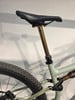 Goldene Sattelstütze mit schwarzem Sattel auf einem hellgrünen Fahrrad.