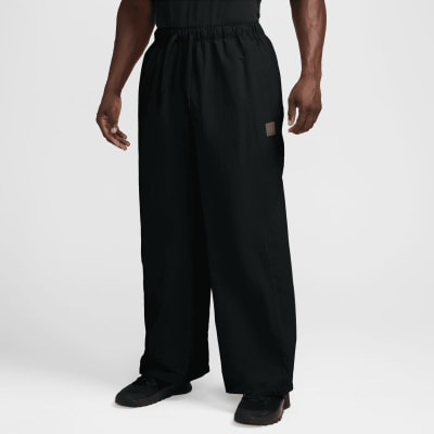 Ein Mann trägt eine schwarze, weite Hose mit einem Logo auf dem linken Oberschenkel. Ein Mann trägt eine schwarze, weite Hose mit einem Logo auf dem linken Oberschenkel.