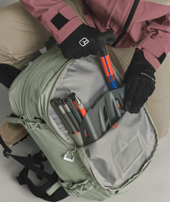 Person in Skijacke packt Pumpe in Rucksack. Person in Skijacke packt Pumpe in Rucksack.