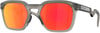 Graue Oakley-Sonnenbrille mit roten Gläsern und Prizm-Logo.
