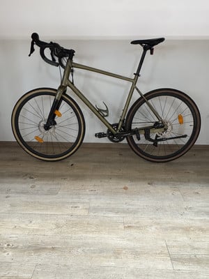 Ein grünes Gravelbike mit schwarzem Lenker und Sattel steht auf einem Holzboden. Ein grünes Gravelbike mit schwarzem Lenker und Sattel steht auf einem Holzboden.