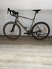 Ein grünes Gravelbike mit schwarzem Lenker und Sattel steht auf einem Holzboden.