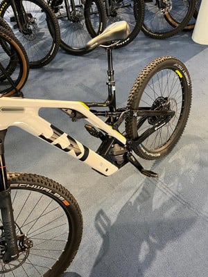 Ein weißes Mountainbike mit schwarzer Federung und Details hängt. Ein weißes Mountainbike mit schwarzer Federung und Details hängt.