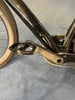 Detail eines schwarzen Fahrrads mit Kurbel und Pedal auf blauem Teppich.