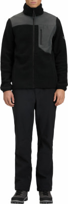 Mann in schwarzer Fleecejacke mit grauen Einsätzen und schwarzer Hose.