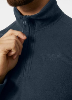Detail eines Mannes in einer dunkelblauen Fleecejacke mit HH-Logo. Detail eines Mannes in einer dunkelblauen Fleecejacke mit HH-Logo.