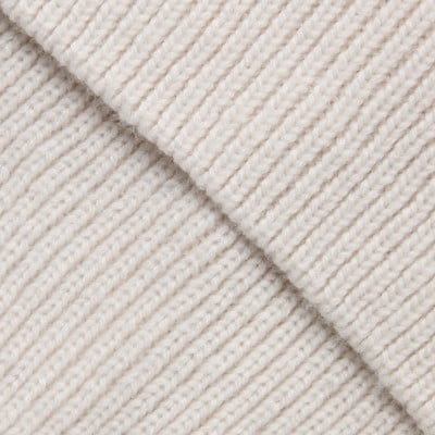 Detail einer cremefarbenen Strickware mit sichtbarer Rippenstruktur. Detail einer cremefarbenen Strickware mit sichtbarer Rippenstruktur.