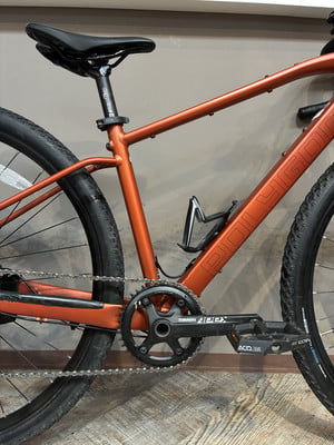 Orangefarbenes Fahrrad mit schwarzem Sattel und SRAM Apex Kurbeln. Orangefarbenes Fahrrad mit schwarzem Sattel und SRAM Apex Kurbeln.