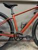 Orangefarbenes Fahrrad mit schwarzem Sattel und SRAM Apex Kurbeln.