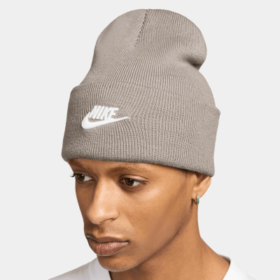 Ein Mann trägt eine graue Nike-Mütze mit weißem Logo und einem Ohrring. Ein Mann trägt eine graue Nike-Mütze mit weißem Logo und einem Ohrring.