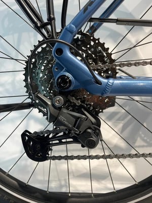 Nahaufnahme einer Shimano CUES Fahrrad-Schaltwerk an einem blauen Rahmen.