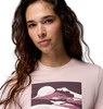 Frau in einem rosa T-Shirt mit Berg- und Sonnenmotiv.