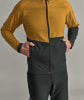 Mann in einer gelb-schwarzen Jacke mit Händen in den Taschen.