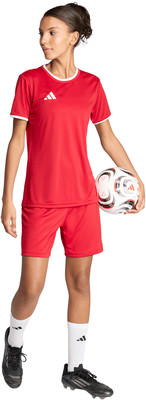 Ein Mädchen im roten Fußballtrikot und Shorts hält einen Fußball. Ein Mädchen im roten Fußballtrikot und Shorts hält einen Fußball.