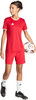 Ein Mädchen im roten Fußballtrikot und Shorts hält einen Fußball.