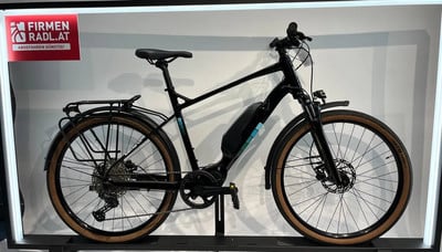 Schwarzes E-Bike mit Gepäckträger und braunen Reifen steht auf einer Ausstellung. Schwarzes E-Bike mit Gepäckträger und braunen Reifen steht auf einer Ausstellung.