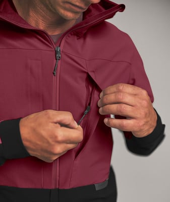 Ein Mann schließt den Reißverschluss einer weinroten Jacke mit schwarzen Ärmeln. Ein Mann schließt den Reißverschluss einer weinroten Jacke mit schwarzen Ärmeln.