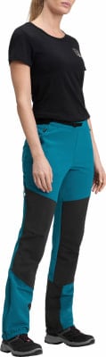 Eine Frau in einem schwarzen T-Shirt und türkisfarbenen Hosen mit schwarzen Einsätzen.