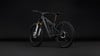 Ein graues Mountain-E-Bike mit Federung und schwarzen Rädern auf dunklem Hintergrund.