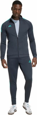 Ein Mann in einem dunkelgrauen Adidas Trainingsanzug mit türkisfarbenen Details.
