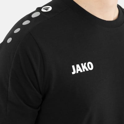 Schwarzes T-Shirt mit JAKO-Logo und weißen Punkten auf der Schulter.