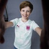 Ein Junge mit Sommersprossen im Trikot mit dem Logo Österreichs und Pumas lächelt.