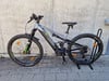 Ein Genesis E-Mountainbike mit Federung und schwarzen Rädern auf einem Ständer.