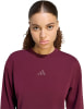 Das Model trägt einen weinroten Pullover mit Adidas-Logo.