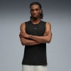 Ein Mann in einem schwarzen Tanktop mit Puma-Logo und verschränkten Armen.
