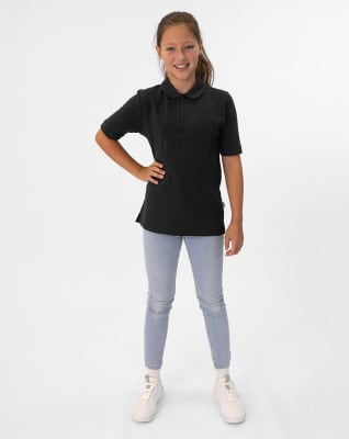 Ein Mädchen in einem schwarzen Poloshirt und Jeans posiert vor weißem Hintergrund. Ein Mädchen in einem schwarzen Poloshirt und Jeans posiert vor weißem Hintergrund.