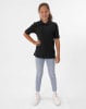 Ein Mädchen in einem schwarzen Poloshirt und Jeans posiert vor weißem Hintergrund.
