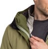 Ein Mann schließt eine grüne Jacke mit schwarzem Kragen und melierter Fütterung.