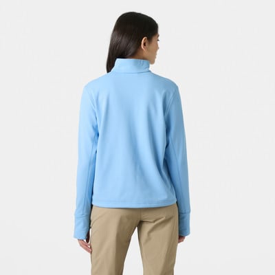 Eine Frau in einem blauen Pullover und einer beige Hose steht mit dem Rücken zum Betrachter. Eine Frau in einem blauen Pullover und einer beige Hose steht mit dem Rücken zum Betrachter.