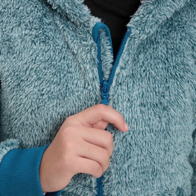Ruka zapína modrý zips na huňatom svetri. Ruka zapína modrý zips na huňatom svetri.