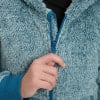 Ruka zapína modrý zips na huňatom svetri.