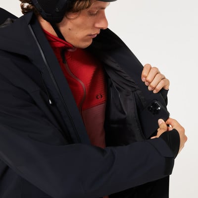 Ein Mann verstaut sein Handy in der Innentasche einer schwarzen Jacke.