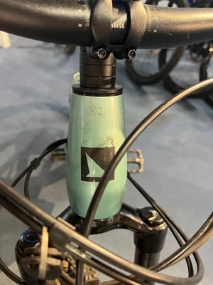 Grüner Fahrradrahmen mit schwarzem Logo und Lenker.