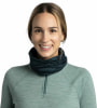 Eine lächelnde Frau trägt einen dunkelblauen Schlauchschal und einen hellgrünen Pullover.