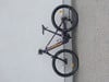Ein lila Mountainbike der Marke LAPIERRE steht an einer grauen Wand.
