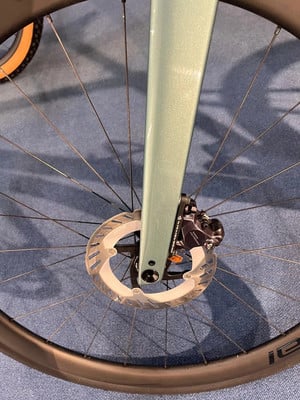 Detail eines Fahrrad-Vorderrads mit Scheibenbremse und Gabel.