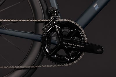 Detail einer Dura-Ace Fahrradkurbel mit Kette und Rahmenteil.