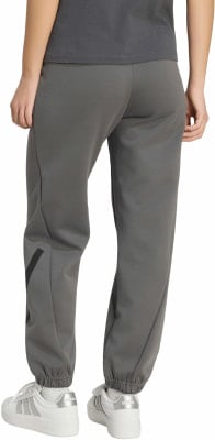 Eine Frau trägt eine dunkelgraue Jogginghose mit einem schwarzen Streifen und weiße Turnschuhe. Eine Frau trägt eine dunkelgraue Jogginghose mit einem schwarzen Streifen und weiße Turnschuhe.