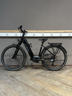 Ein schwarzes KTM E-Bike steht auf einem Holzboden vor einer grauen Wand. Ein schwarzes KTM E-Bike steht auf einem Holzboden vor einer grauen Wand.